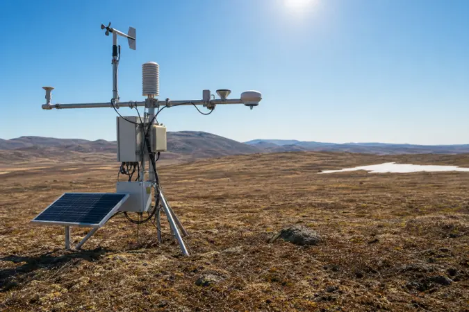 A weather station on a sunlit tundra landscape in northern Russia, with patches of thawed ground and distant low hills.