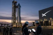 A SpaceX Starship-style rocket stands at a launch facility at dusk as engineers monitor operations nearby.