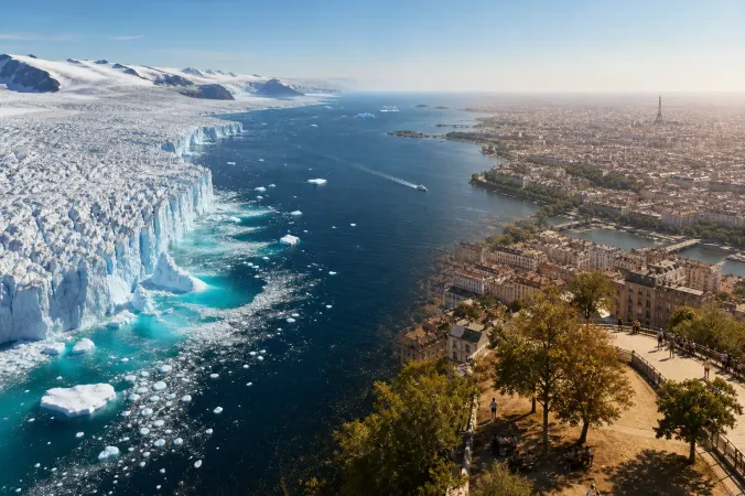 Aerial view of Greenland glacier meltwater flowing into a cold North Atlantic sea, with a sunlit European city under hazy high-pressure summer skies in the distance.